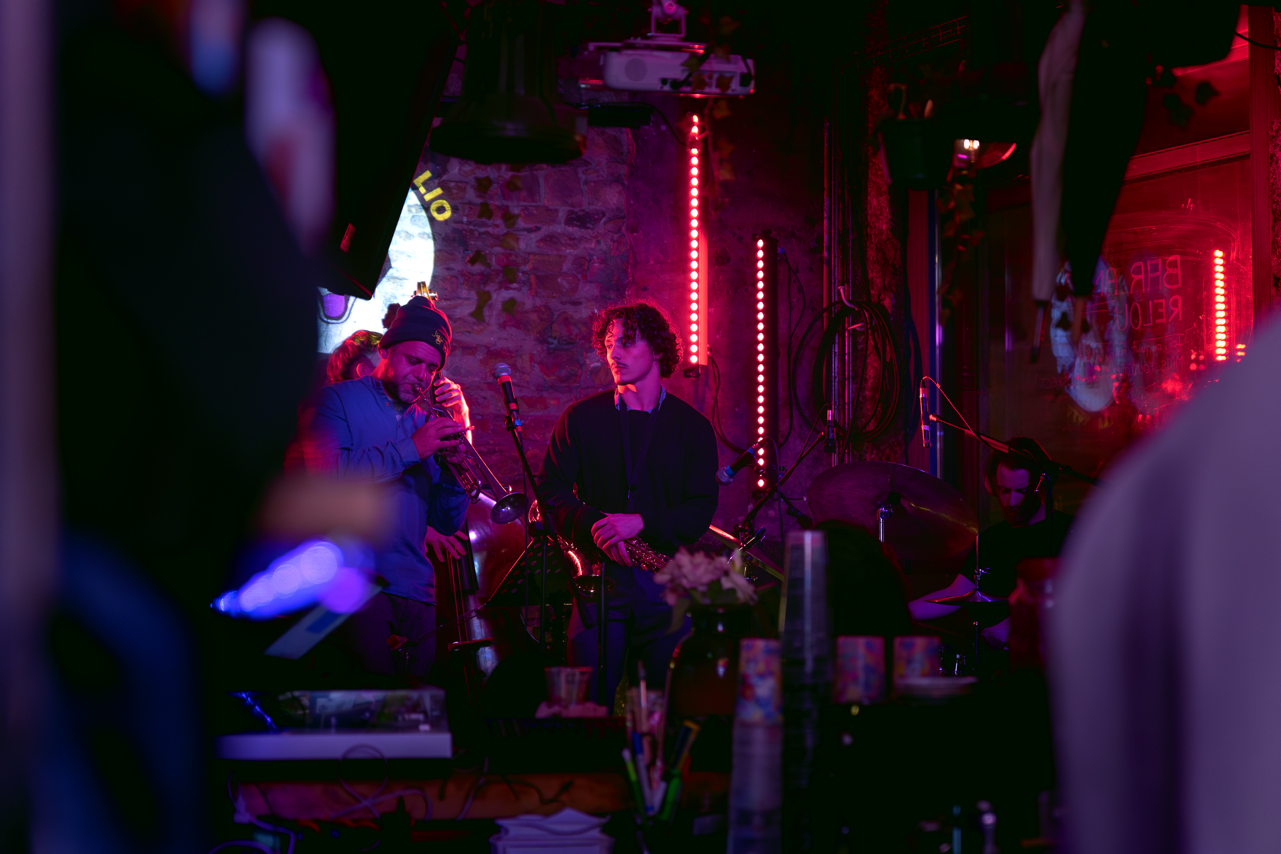 photo d'une scène avec des musiciens qui jouent. composé d'un trompettiste, d'un saxophoniste et d'un batteur.